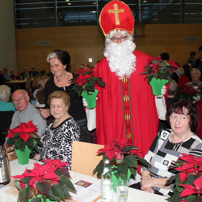 Bild vergrern: Der Nikolaus brachte allen Besuchern einen Weihnachtsstern mit. Die Mitglieder des Seniorenbeirates halfen bei der Verteilung.