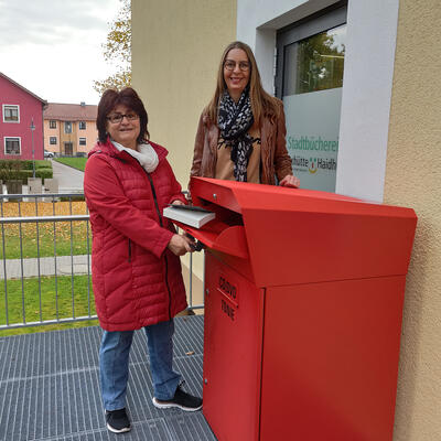 Bild vergrößern: Das Bild zeigt die Leserin Evi Pointner aus Maxhütte-Haidhof beim ersten Einwurf in die Rückgabebox mit der stellvertretenden Büchereileiterin Sibylle Neumann.